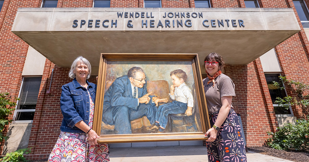 Professor emerita Patricia Zebrowski and assistant professor Naomi Rodgers hold a painting of Wendell Johnson